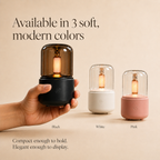 Vellura Living diffuser shown in black, white, and pink color options, with a hand holding the compact black diffuser against a soft neutral background.